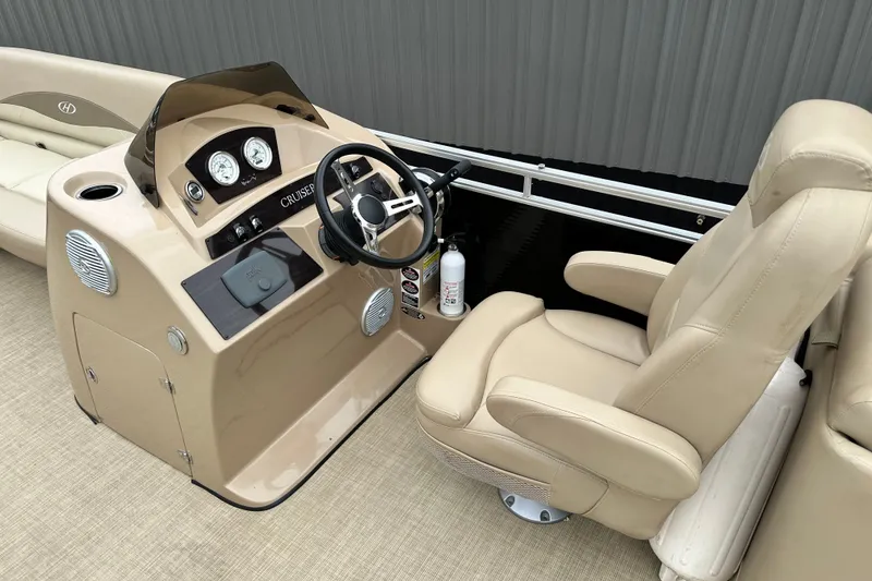 Slide: The Image of 2016 Harris Cruiser 240 boat interior with beige captain's chair and control panel. - 10