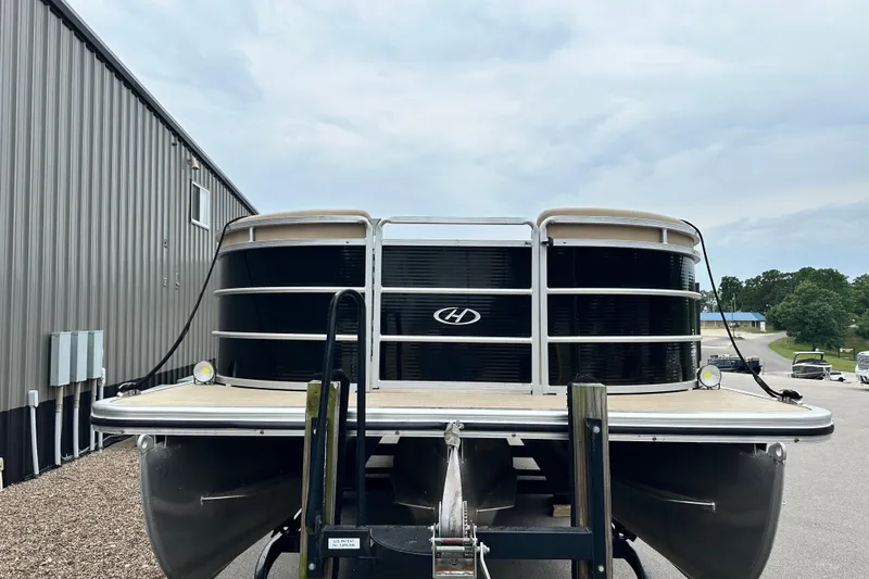 Slide: The Image of 2016 Harris Cruiser 240 pontoon boat parked near a metal building. - 2