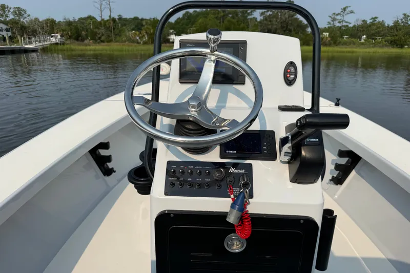 Slide: The Image of 2020 Maverick 18 HPX-V boat console with steering wheel and controls on calm water. - 21
