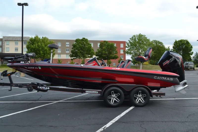 The Image of 2021 Caymas CX 19 boat in parking lot, red and black design, on trailer. - 0