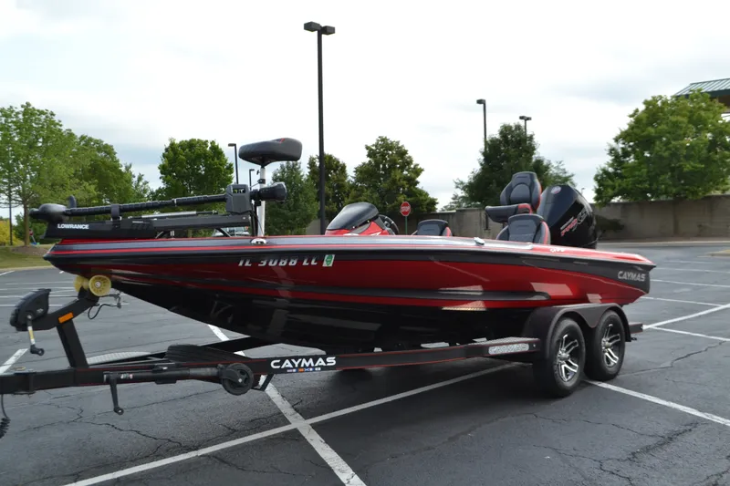 Slide: The Image of 2021 Caymas CX 19 boat on trailer in parking lot, featuring red and black design. - 1
