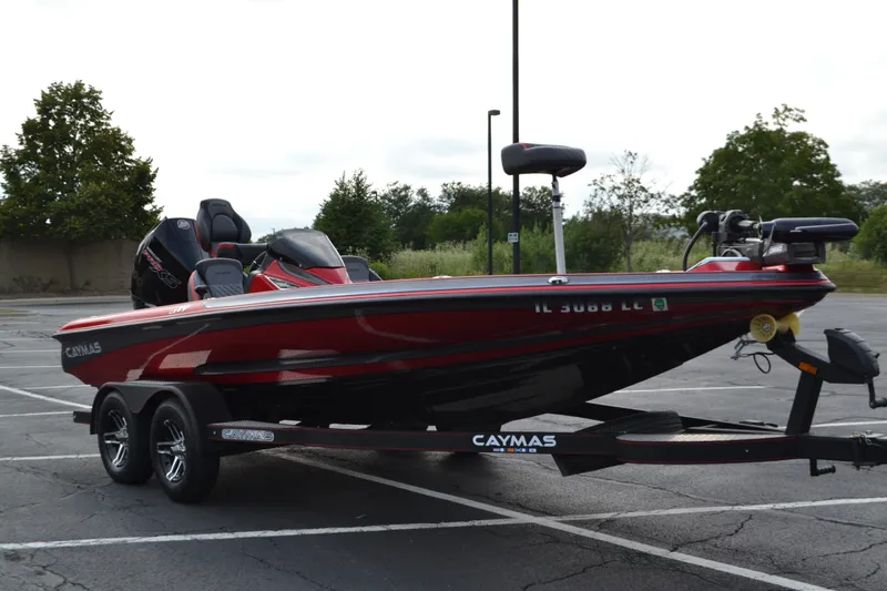 Slide: The Image of 2021 Caymas CX 19 boat on trailer in parking lot, red and black design. - 5
