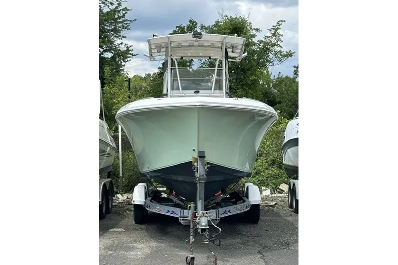 Slide: The Image of 2007 Sailfish 2360 CC boat on trailer, parked outdoors with trees in background. - 16
