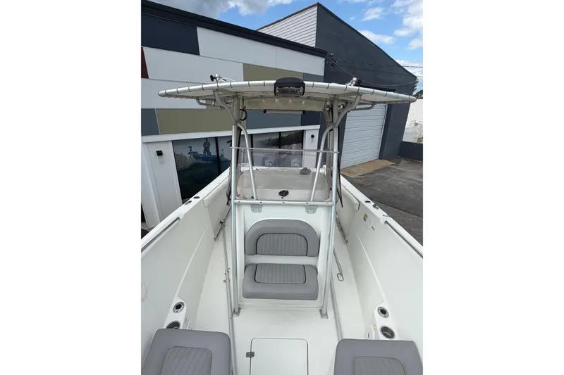 Slide: The Image of 2007 Sailfish 2360 CC boat with T-top and seating, docked near modern building. - 9