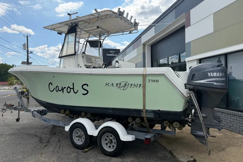 Slide: The Image of 2007 Sailfish 2360 CC boat on trailer with Yamaha outboard motor, parked outside a building. - 2