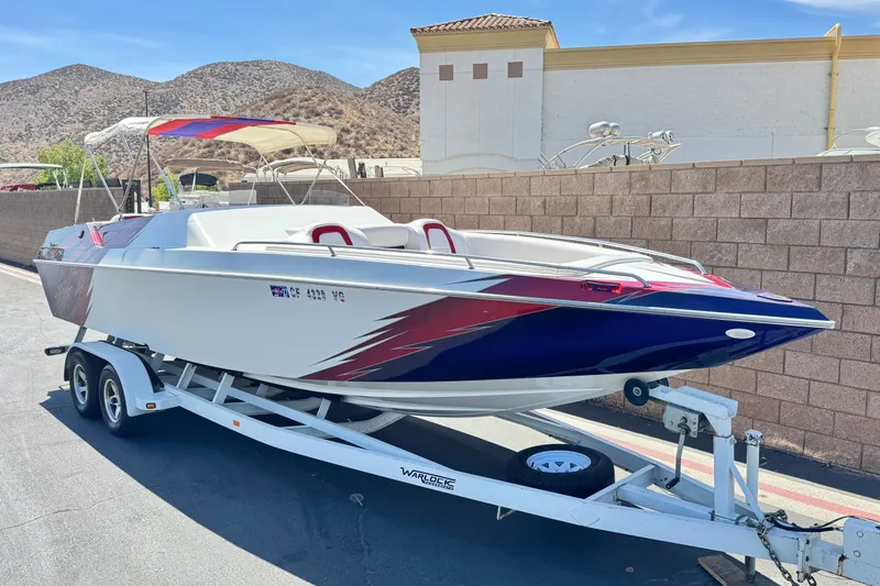 Slide: The Image of 2005 Ultimate Warlock 25 World Class boat on trailer, parked near a brick wall. - 1