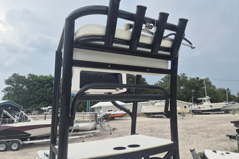Slide: The Image of 2018 Mako Pro Skiff 19 CC Top Drive with rod holders in a boatyard setting. - 10
