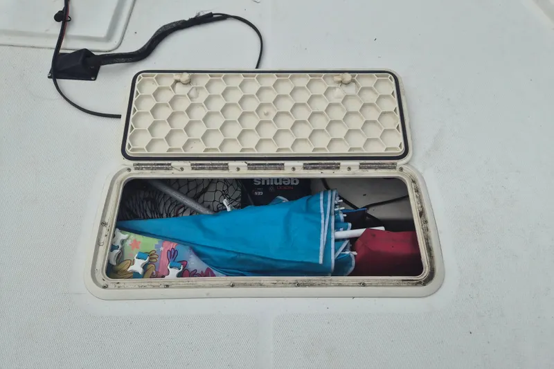 Slide: The Image of Open storage compartment on 2018 Mako Pro Skiff 19 CC Top Drive boat, containing colorful items. - 15