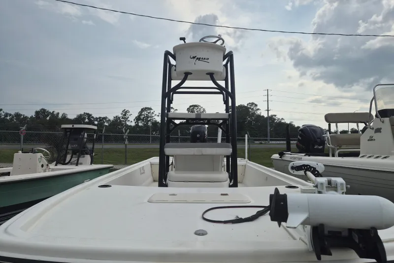 Slide: The Image of 2018 Mako Pro Skiff 19 CC Top Drive boat with elevated helm, parked outdoors. - 2