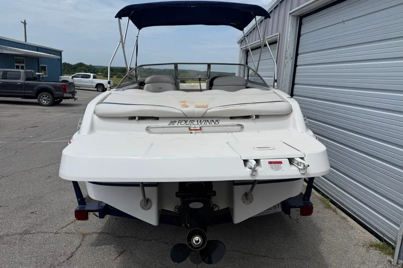 Slide: The Image of 2003 Four Winns 190 Horizon boat with canopy, parked near a garage. - 2