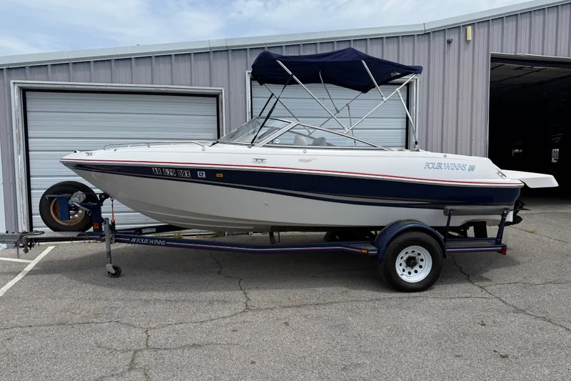 The Image of 2003 Four Winns 190 Horizon boat on trailer, parked outside a garage. - 0