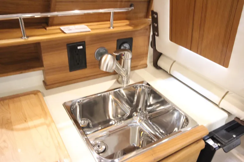 Slide: The Image of 2026 Ranger Tugs R-27 boat kitchen sink with wooden cabinetry and modern fixtures. - 13