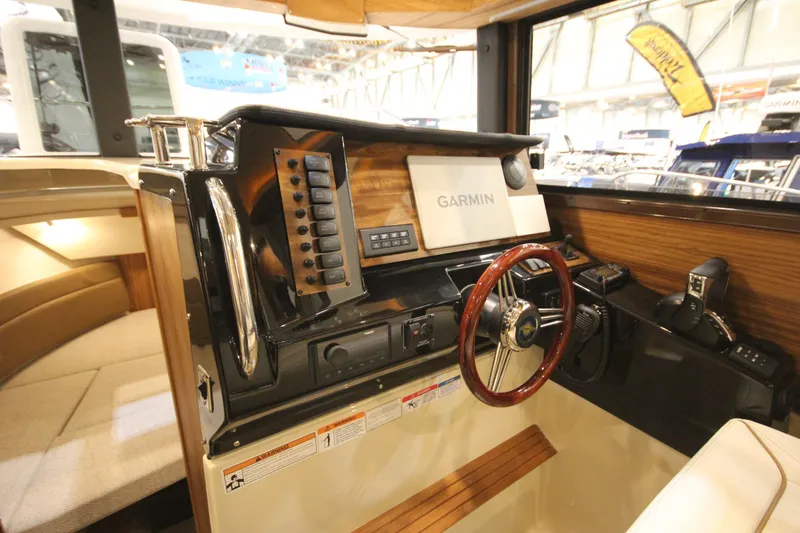 Slide: The Image of 2026 Ranger Tugs R-27 helm with Garmin navigation, wood accents, and modern controls. - 15