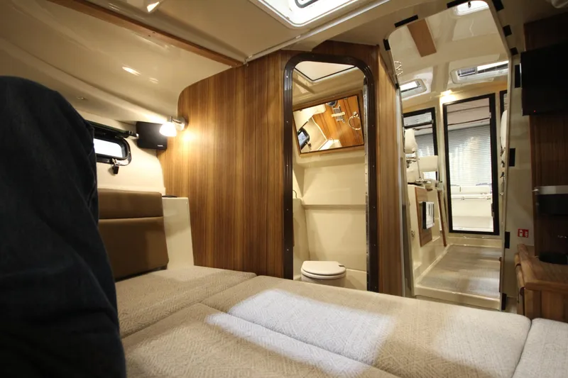 Slide: The Image of 2026 Ranger Tugs R-27 interior cabin with wood paneling and modern amenities. - 23