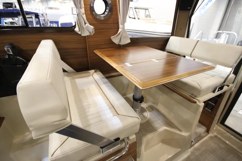 Slide: The Image of 2026 Ranger Tugs R-27 interior with wooden table and white seating. - 15
