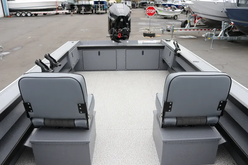 Slide: The Image of 2027 Alumaweld Super Vee Pro 23 boat interior with seating and motor, in a marina setting. - 16