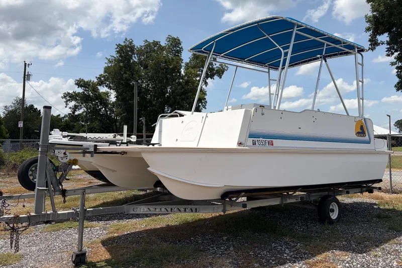 The Image of 1998 Beachcat 19 boat on trailer with blue canopy, parked outdoors under cloudy sky. - 1