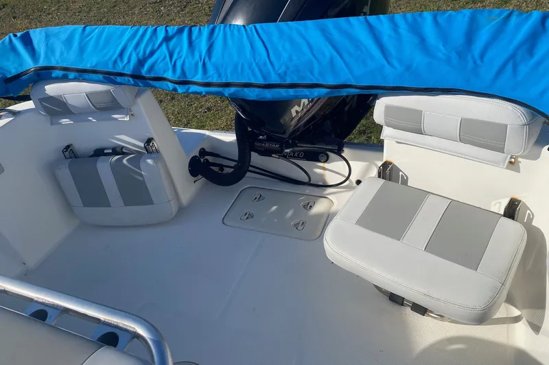 Slide: The Image of 2018 Mako 204 Center Console boat interior with cushioned seating and engine cover. - 11