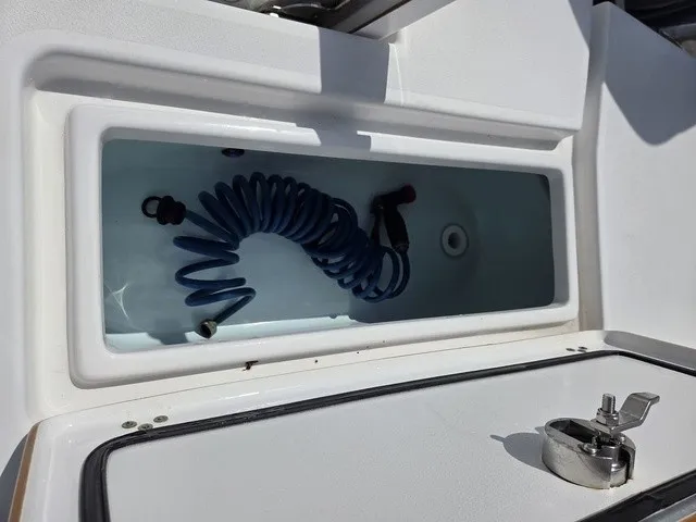 Slide: The Image of An open storage compartment on a 2020 Sportsman Masters 247 Bay Boat with a blue hose. - 26