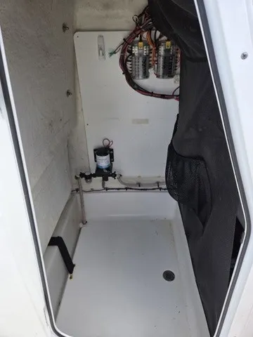 Slide: The Image of An open storage compartment with wiring and a small pump on the wall. - 13