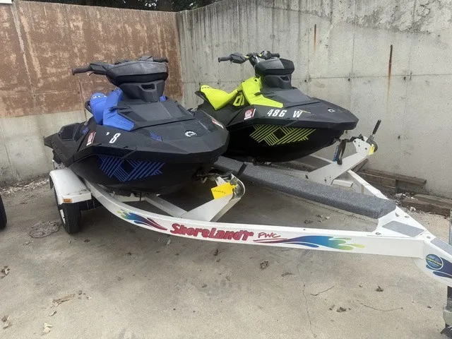 Slide: The Image of Two Sea-Doo Spark Trixx jet skis, blue and yellow, on a trailer in a concrete area. - 12