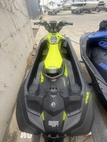 Slide: The Image of A bright yellow Sea-Doo Spark Trixx jet ski sits on concrete ground next to other boats. - 9