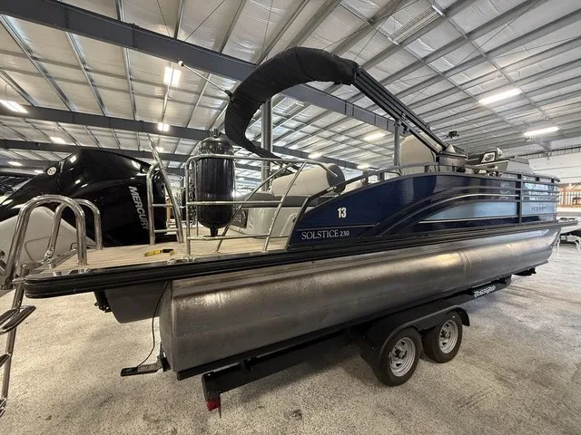 Slide: The Image of A 2021 Harris Solstice 250 SLDH pontoon boat on a trailer inside a warehouse. - 9
