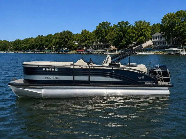 Slide: The Image of A 2021 Harris Solstice 250 SLDH pontoon boat on a calm lake with trees in the background. - 1