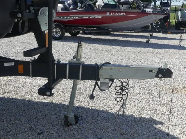 Slide: The Image of A boat trailer with a jack wheel and safety cable on a gravel lot. - 8
