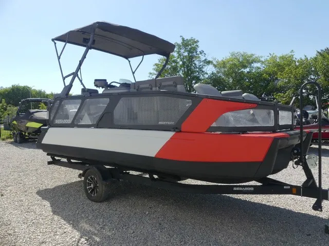 Slide: The Image of A 2023 Sea-Doo Switch Sport 21 on a trailer, featuring a red and black design, parked on gravel. - 25