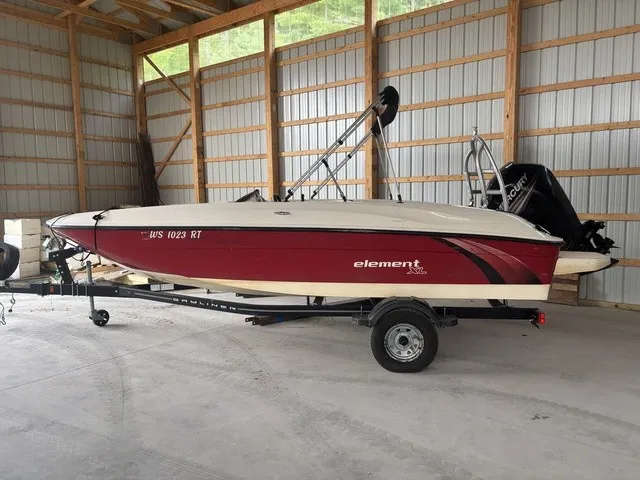 The Image of 2016 Bayliner Element in a storage shed, red and white, on a trailer. - 1