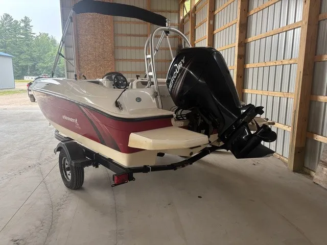 Slide: The Image of A red 2016 Bayliner Element boat is in a warehouse. It features a Mercury outboard motor. - 6