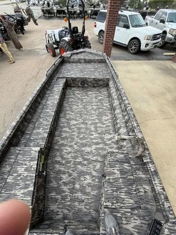 Slide: The Image of The image shows a camouflaged open cabin boat parked in a lot. - 25