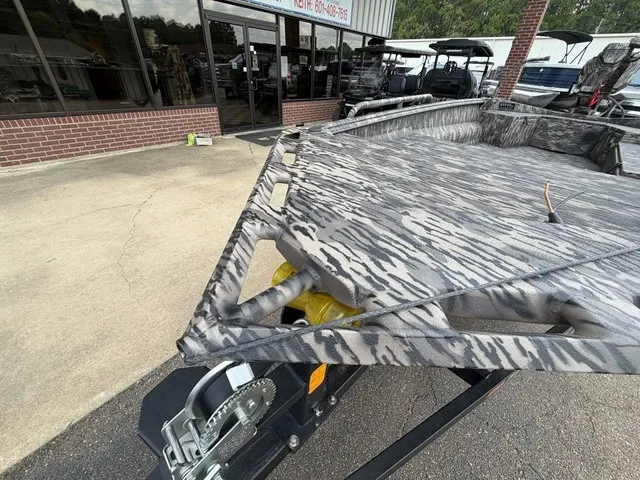 Slide: The Image of A 2026 Havoc 1756 MSTC boat with a camo design, on a trailer in front of a building. - 2