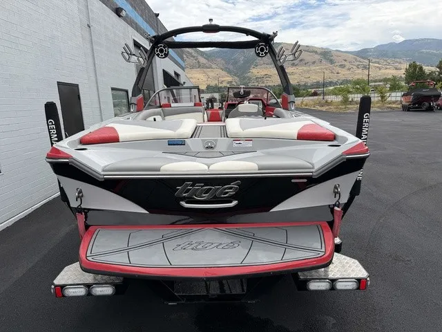 Slide: The Image of A 2018 Tigé R23 boat with red and white upholstery, parked in front of a building. - 6