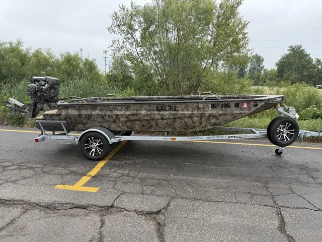 The Image of An Excel 175 SWF4 Legacy boat on a trailer, parked on a road beside trees. - 1