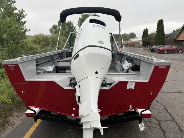 Slide: The Image of Red boat with white outboard motor, parked on a trailer, surrounded by trees and cars. - 10