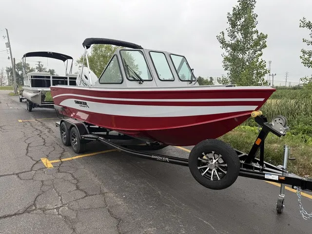 Slide: The Image of A red boat with white stripes is on a trailer in a parking lot. - 2