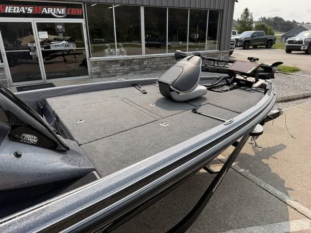 Slide: The Image of A 2022 Phoenix 721 ProXP bass boat with a gray deck and seat, parked in front of a building. - 9