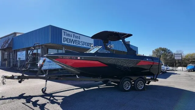 The Image of A black and red ATX boat, model 22 S, is on a trailer in front of a building. - 1