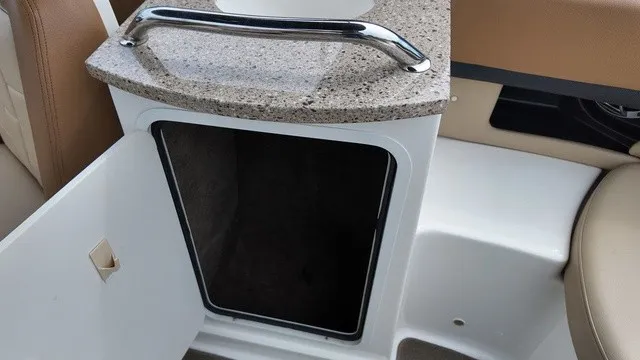 Slide: The Image of An open storage compartment with a granite countertop and metal handle on a Sea Ray SLX 250 boat. - 32