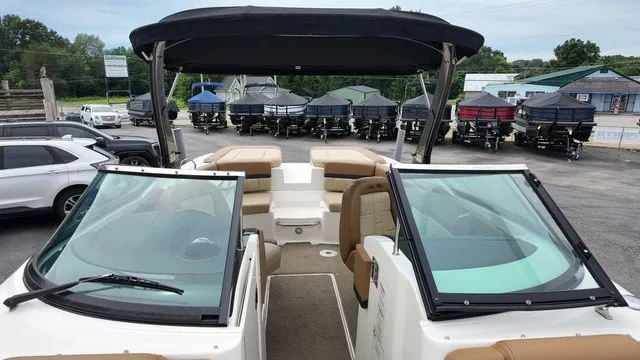 Slide: The Image of A 2015 Sea Ray SLX 250 with brown seating and black canopy, parked in a lot. - 30