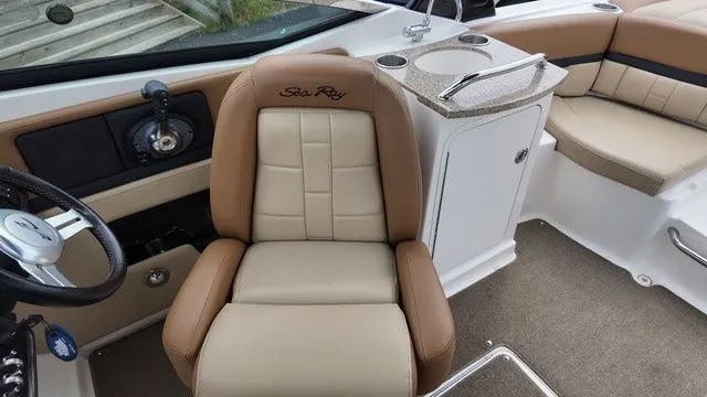Slide: The Image of The interior of a 2015 Sea Ray SLX 250 with beige and brown seating and a helm console. - 24