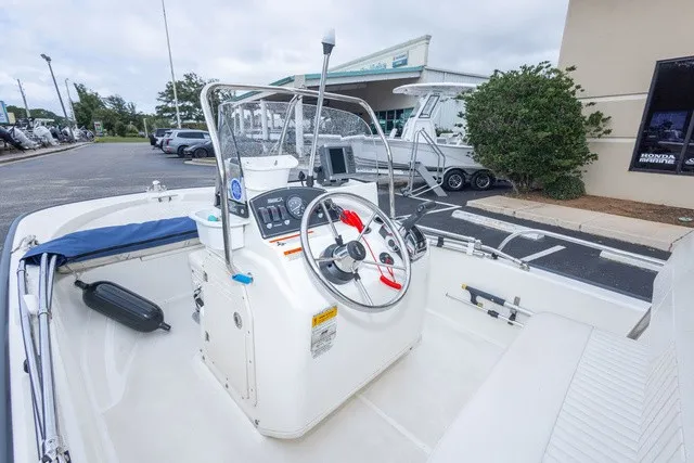 Slide: The Image of The image shows a 2012 Boston Whaler 150 Montawk boat with a central helm station. - 14