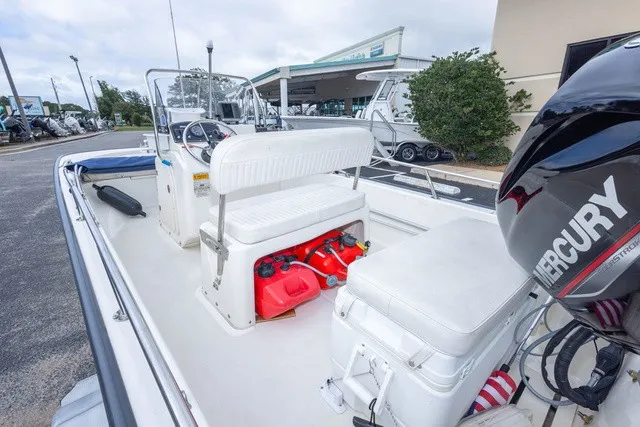 Slide: The Image of A 2012 Boston Whaler 150 Montawk with white interior and a Mercury engine, outdoors. - 12