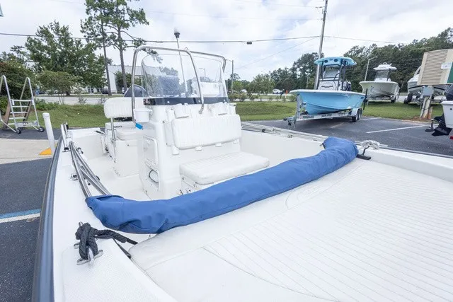 Slide: The Image of A 2012 Boston Whaler 150 Montawk on a parking lot. It features an open deck and a blue cover. - 10