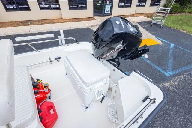 Slide: The Image of A 2012 Boston Whaler 150 Montawk with a Mercury outboard motor. There's a seating area and fuel canisters. - 21