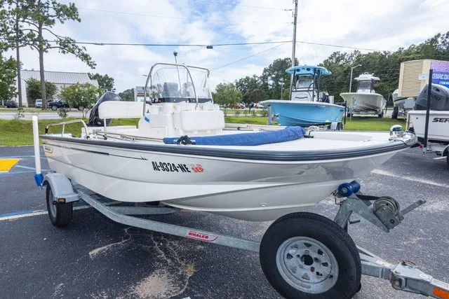 The Image of A 2012 Boston Whaler 150 Montawk on a trailer in a parking lot. - 1