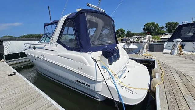 The Image of A white 2001 Mustang 3200 Sport Cruiser docked, featuring a blue canopy. - 1