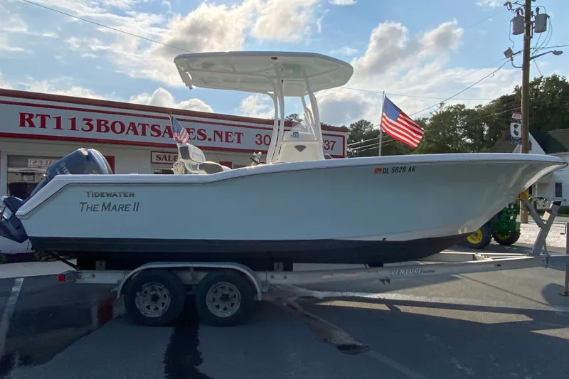 The Image of 2015 Tidewater 230 CC Adventure boat on trailer at dealership, American flag visible. - 1
